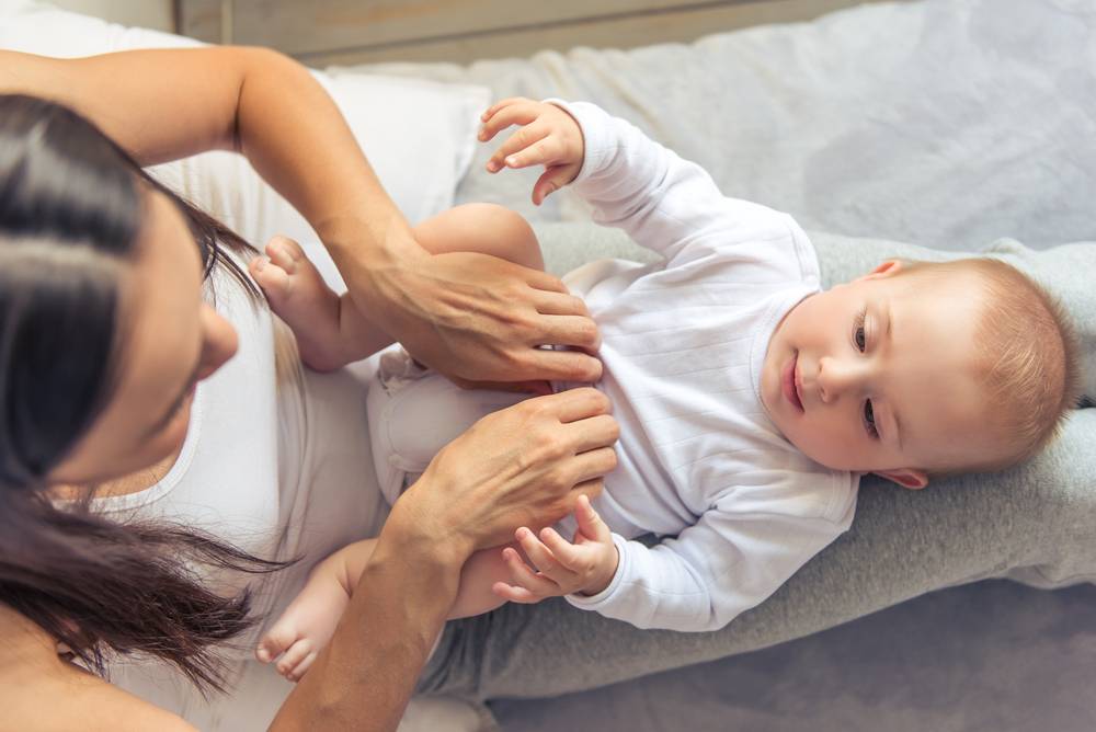 young mother dressing her baby in longsleeve